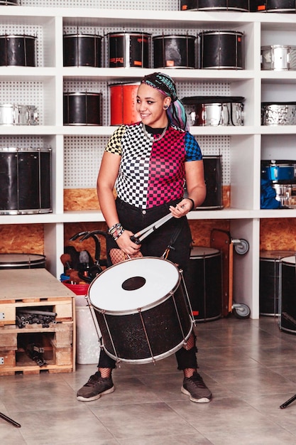 Retrato de uma menina sorridente com um tambor e baquetas dentro de um estúdio