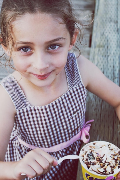 Retrato de uma menina sorridente comendo sorvete