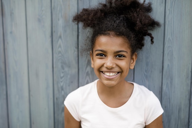 Foto retrato de uma menina sorridente contra painéis de madeira