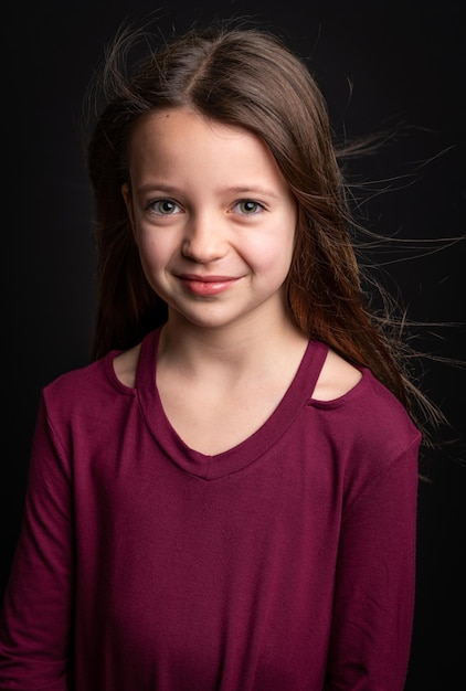 Foto retrato de uma menina sorridente contra um fundo preto