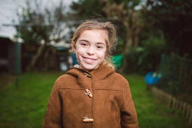 Retrato de uma menina sorridente de pé contra as árvores