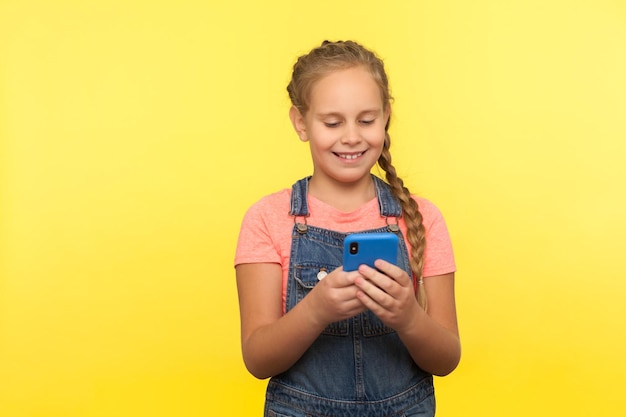 Foto retrato de uma menina sorridente de pé contra um fundo amarelo