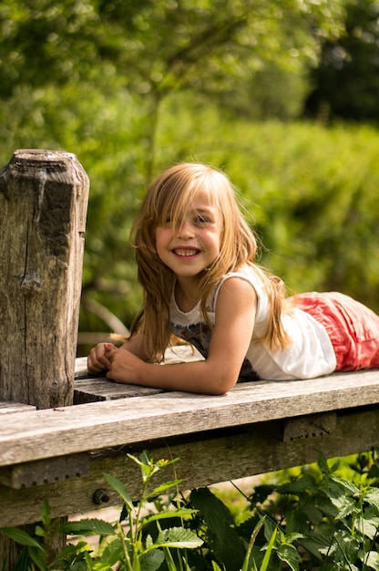 Retrato de uma menina sorridente deitada no cais