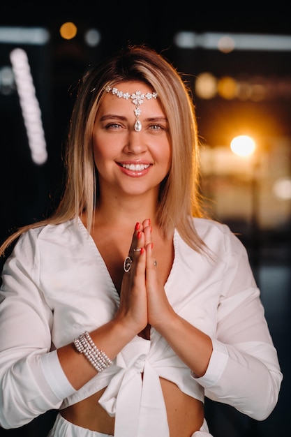 Retrato de uma menina sorridente em um vestido branco com as palmas das mãos na frente dela