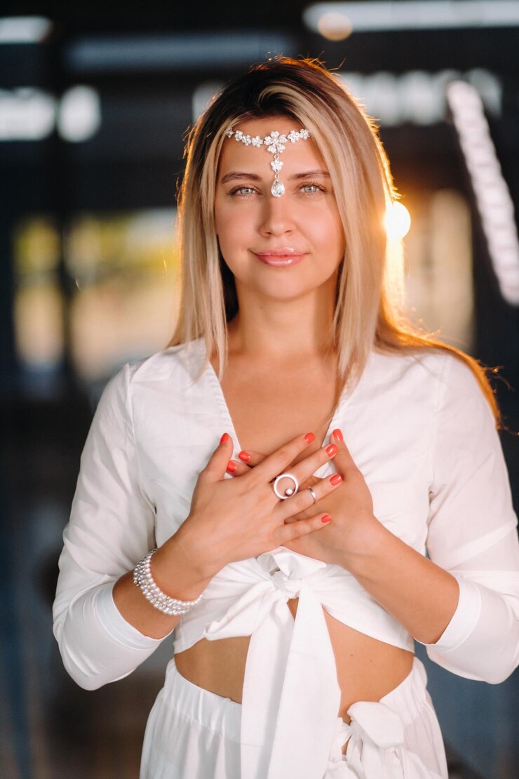 Foto retrato de uma menina sorridente em um vestido branco com as palmas das mãos na frente dela