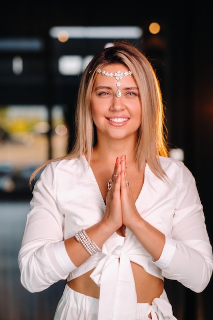 Retrato de uma menina sorridente em um vestido branco com as palmas das mãos na frente dela