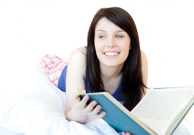 Retrato de uma menina sorridente estudando mentindo em uma cama