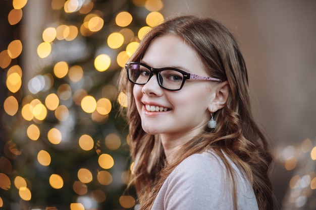 Retrato de uma menina sorridente no fundo de uma árvore de ano novo no Natal