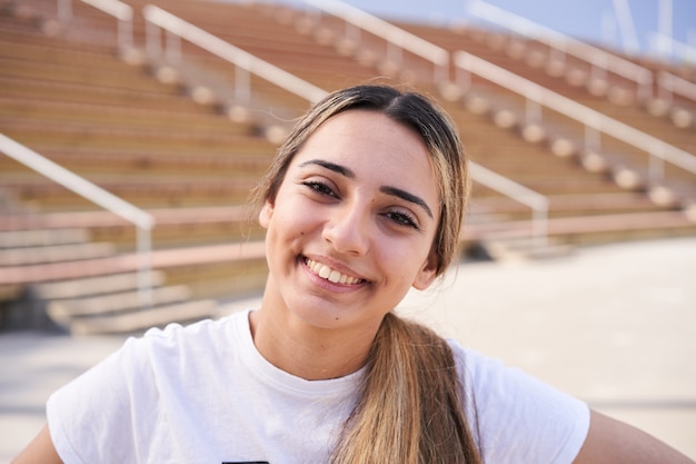 retrato de uma menina sorridente, olhando para a câmera com o plano de fundo do estádio