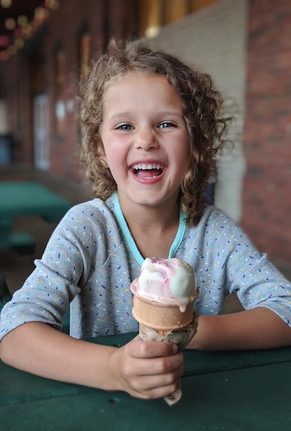 Retrato de uma menina sorridente segurando um sorvete
