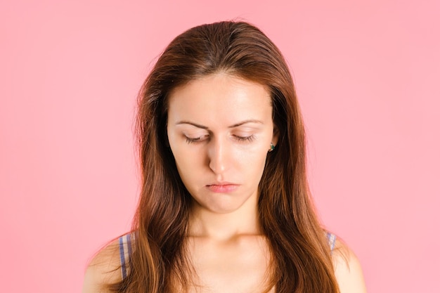 Retrato de uma menina triste e infeliz em um fundo rosa