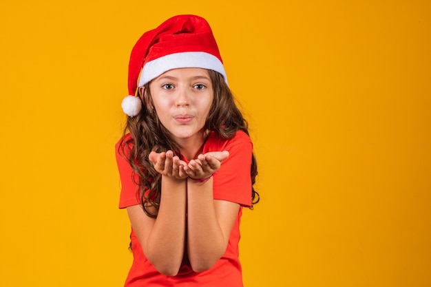 Retrato de uma menina vestida com roupas de natal, soprando algo nas mãos.