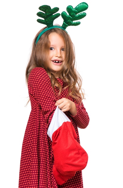 Retrato de uma menina vestindo um chapéu de Papai Noel Criança feliz com chifres de Natal engraçados de um cervo isolado em fundo branco Conceito de feriado Criança engraçada com meia de Natal