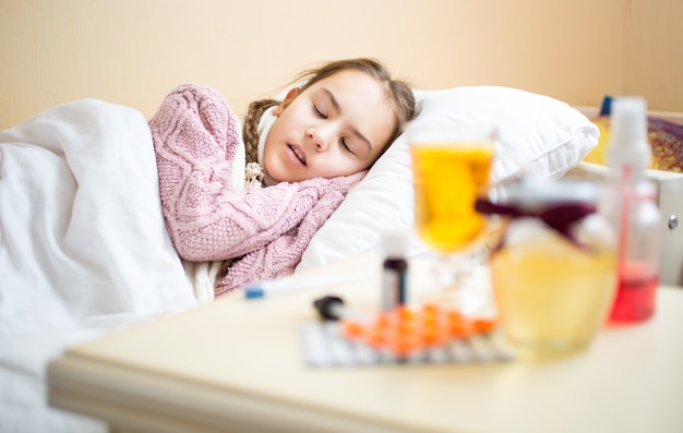 Retrato de uma mesa com medicamentos em pé ao lado da cama das meninas doentes