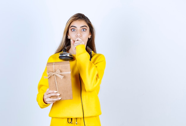 Retrato de uma modelo de menina segurando uma caixa de papel com um laço isolado na parede branca