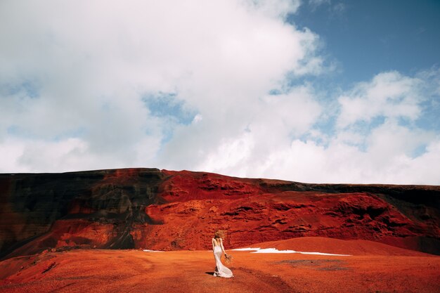 Retrato de uma modelo de noiva em um vestido de noite de casamento dourado em uma pedreira de areia amarelo-avermelhada no