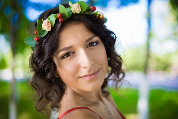 Retrato de uma morena com flores no cabelo em um parque verde.