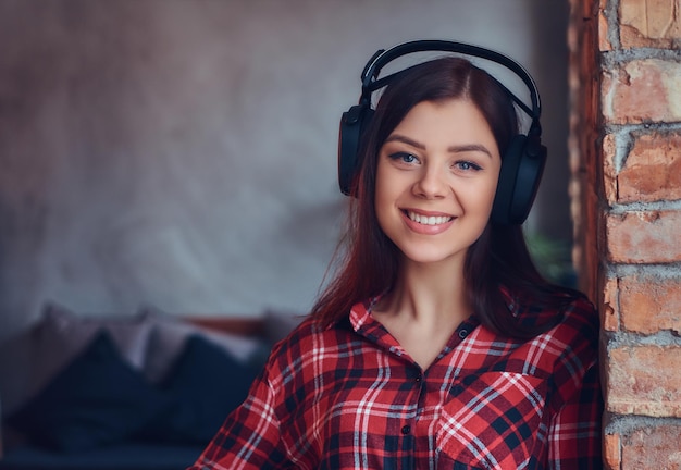 Retrato de uma morena encantadora em uma camisa de flanela e jeans lis