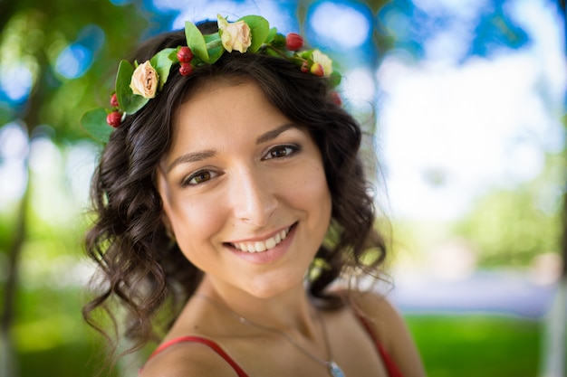 Retrato de uma morena sexy com flores no cabelo em um parque verde. Primavera de menina.