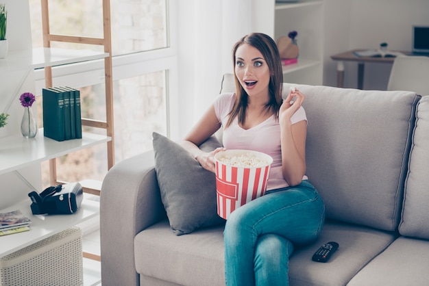 Foto retrato de uma mulher adorável assistindo tv com uma caixa de milho grande