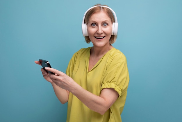 Retrato de uma mulher adulta loira com fones de ouvido e um smartphone nas mãos