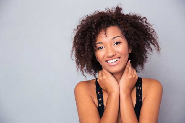 Retrato de uma mulher afro-americana alegre em pé sobre uma parede cinza