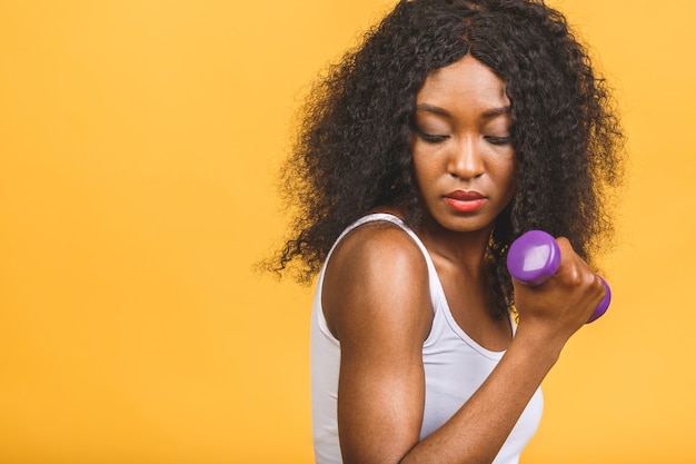 Retrato de uma mulher afro-americana exercitando seus músculos com halteres