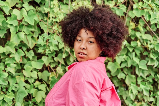 Retrato de uma mulher afro-americana olhando para a câmera com cabelos cacheados e um corpo curvilíneo