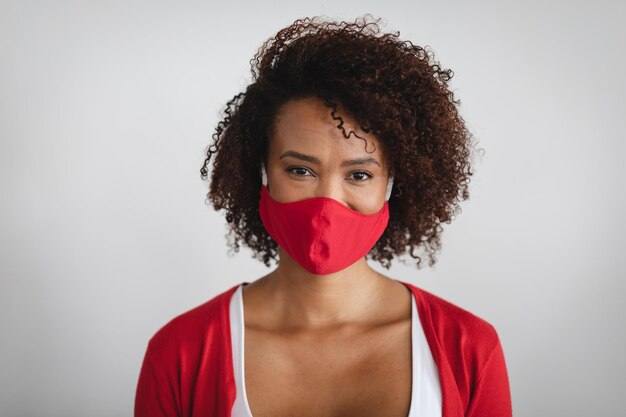 Retrato de uma mulher afro-americana usando máscara facial contra um fundo cinza. higiene e precauções para prevenção de infecções durante a pandemia de coronavírus covid 19.