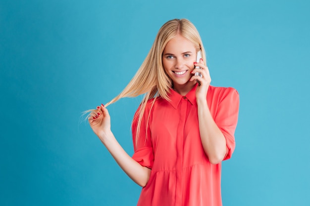 Retrato de uma mulher alegre e casual falando ao telefone na parede azul