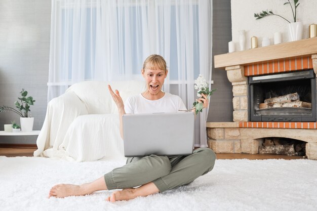 Retrato de uma mulher alegre em casa com um laptop, conectado online a uma reunião com amigos.