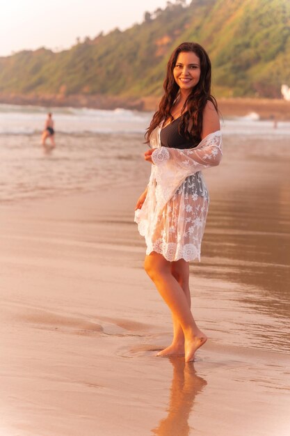 Retrato de uma mulher ao pôr do sol em um vestido branco, aproveitando as férias