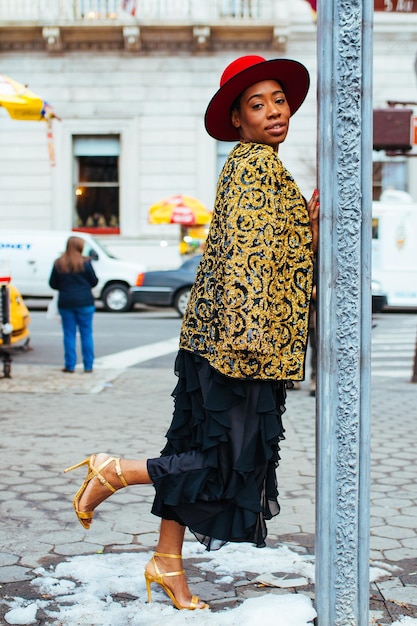 Foto retrato de uma mulher apoiada em um poste enquanto está de pé em uma calçada na cidade