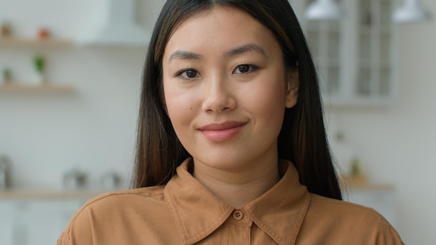 Retrato de uma mulher asiática de etnia coreana sorrindo, uma moça chinesa, uma mulher de negócios na cozinha doméstica.