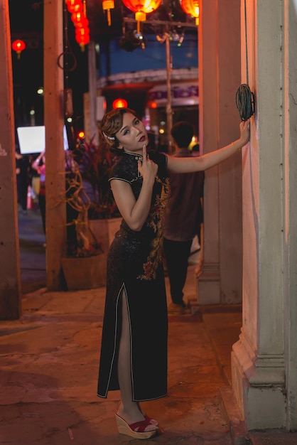 Retrato de uma mulher asiática de vestido preto na passarela na cena noturna do centro fecha um estilo de rua de menina