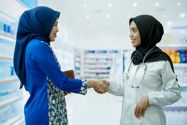 Retrato de uma mulher asiática farmacêutica e um médico apertando as mãos na loja de farmácia