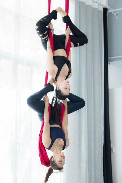 Foto retrato de uma mulher asiática feliz em uma aula de ioga aérea. uma mulher asiática fazendo exercícios de alongamento de ioga com mosca.