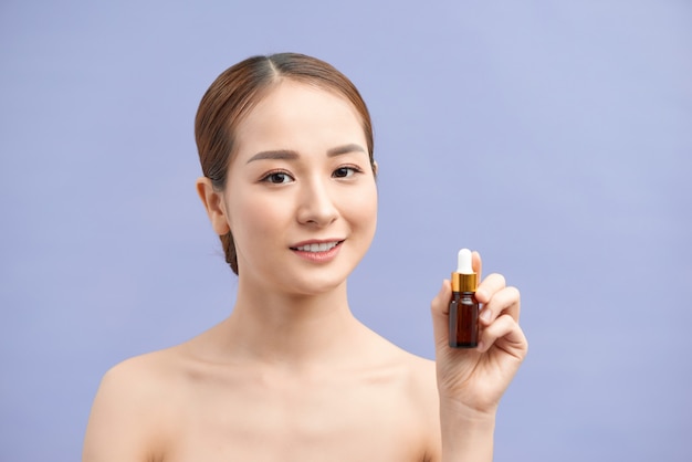 Retrato de uma mulher asiática saudável e sorridente segurando um recipiente de cosméticos