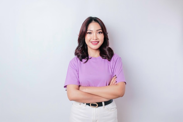 Retrato de uma mulher asiática sorridente confiante de pé com os braços cruzados e olhando para a câmera isolada sobre fundo branco