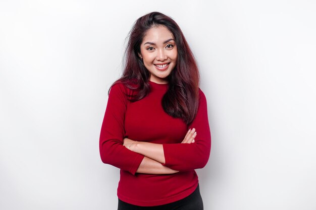 Retrato de uma mulher asiática sorridente confiante vestida de vermelho em pé com os braços cruzados e olhando para a câmera isolada sobre fundo branco