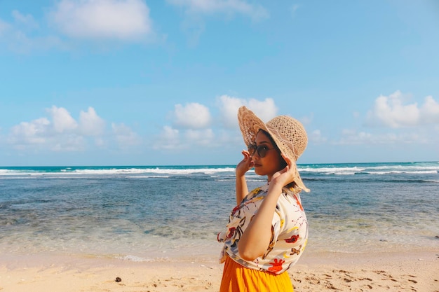 Retrato de uma mulher asiática sorridente feliz na praia usa chapéu