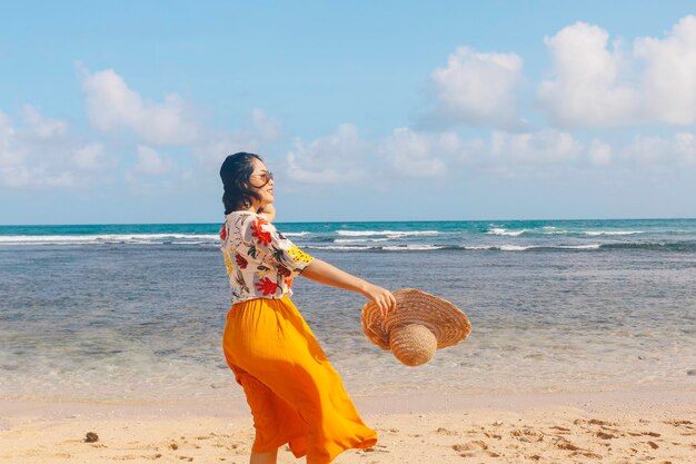 Retrato de uma mulher asiática sorridente feliz na praia usa chapéu