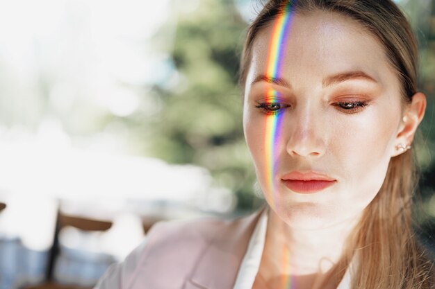 Retrato de uma mulher atraente com luz de arco-íris no rosto