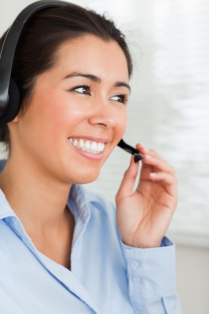 Foto retrato de uma mulher atraente com um fone de ouvido ajudando clientes enquanto está sentado