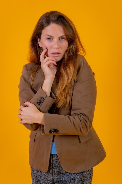 Retrato de uma mulher atraente de olhos azuis em um fundo amarelo em um conceito de moda de jaqueta marrom