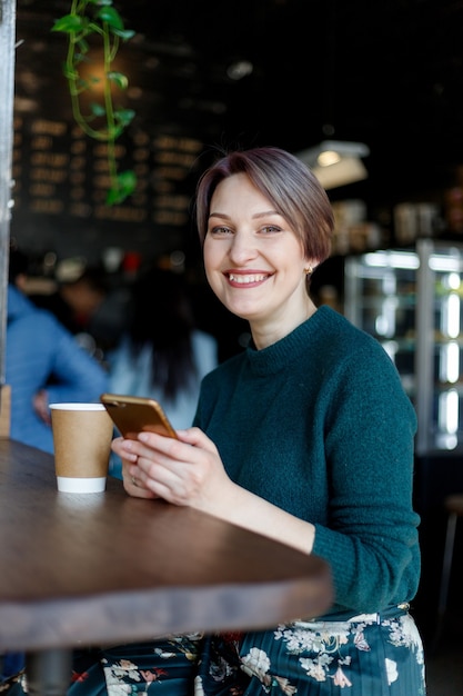 Retrato de uma mulher atraente e elegante, sentada em um café.