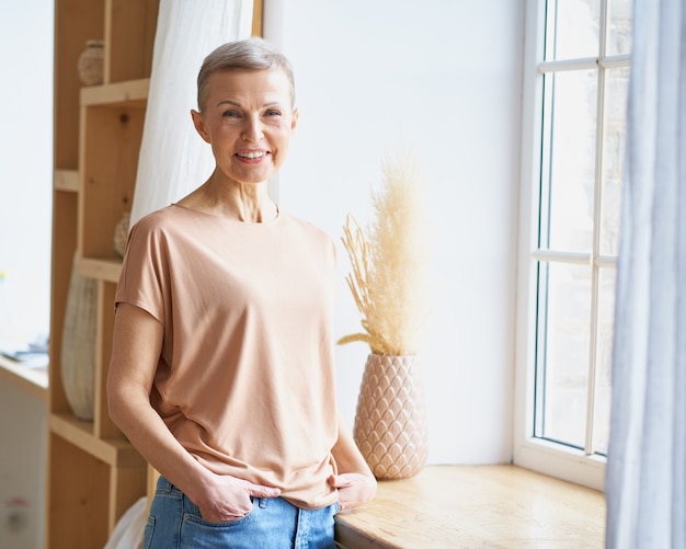 Retrato de uma mulher atraente feliz de meia-idade em roupa casual, mantendo as mãos nos bolsos da calça jeans