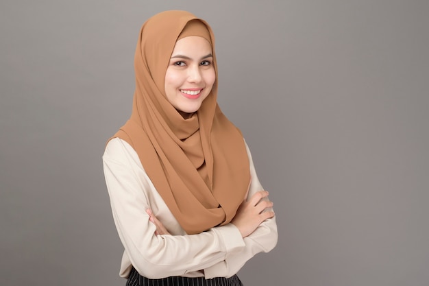 Retrato de uma mulher bonita com hijab está sorrindo em fundo cinza