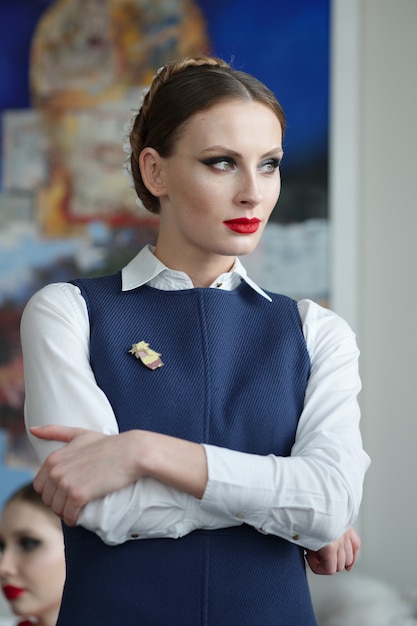 Foto retrato de uma mulher bonita com maquiagem brilhante e lábios vermelhos na camisa branca com jaqueta sem mangas