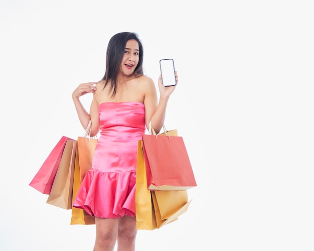 Retrato de uma mulher bonita com sacolas de compras e smartphone na superfície branca, espaço para texto